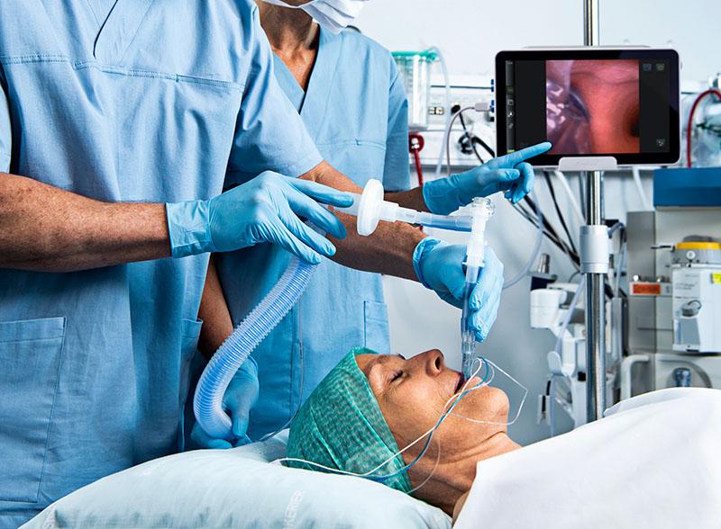 Sjukvårdspersonal utför enlungsventilation med dubbellumentuben Ambu VivaSight 2 DLT på liggande patient med monitorn aView 2 Advance i bakgrunden