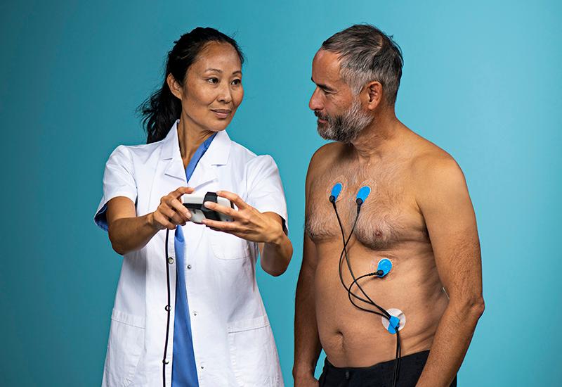 Patient med BlueSensor elektroder blir instruerad av sjukvårdspersonal inför ett långtids-EKG